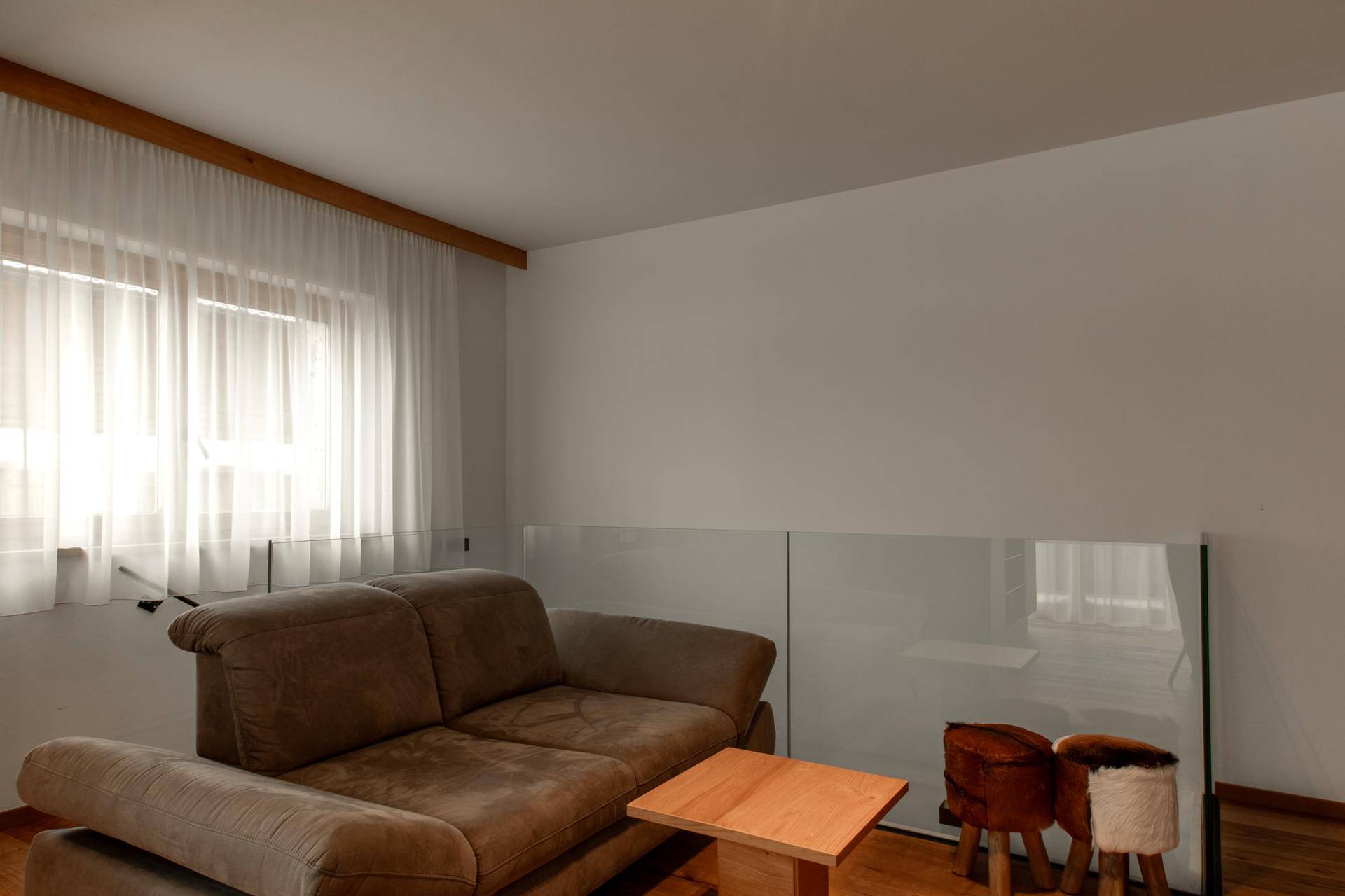 Gemütlicher Wohnbereich mit Sofa, Holztisch und großen Fenstern.