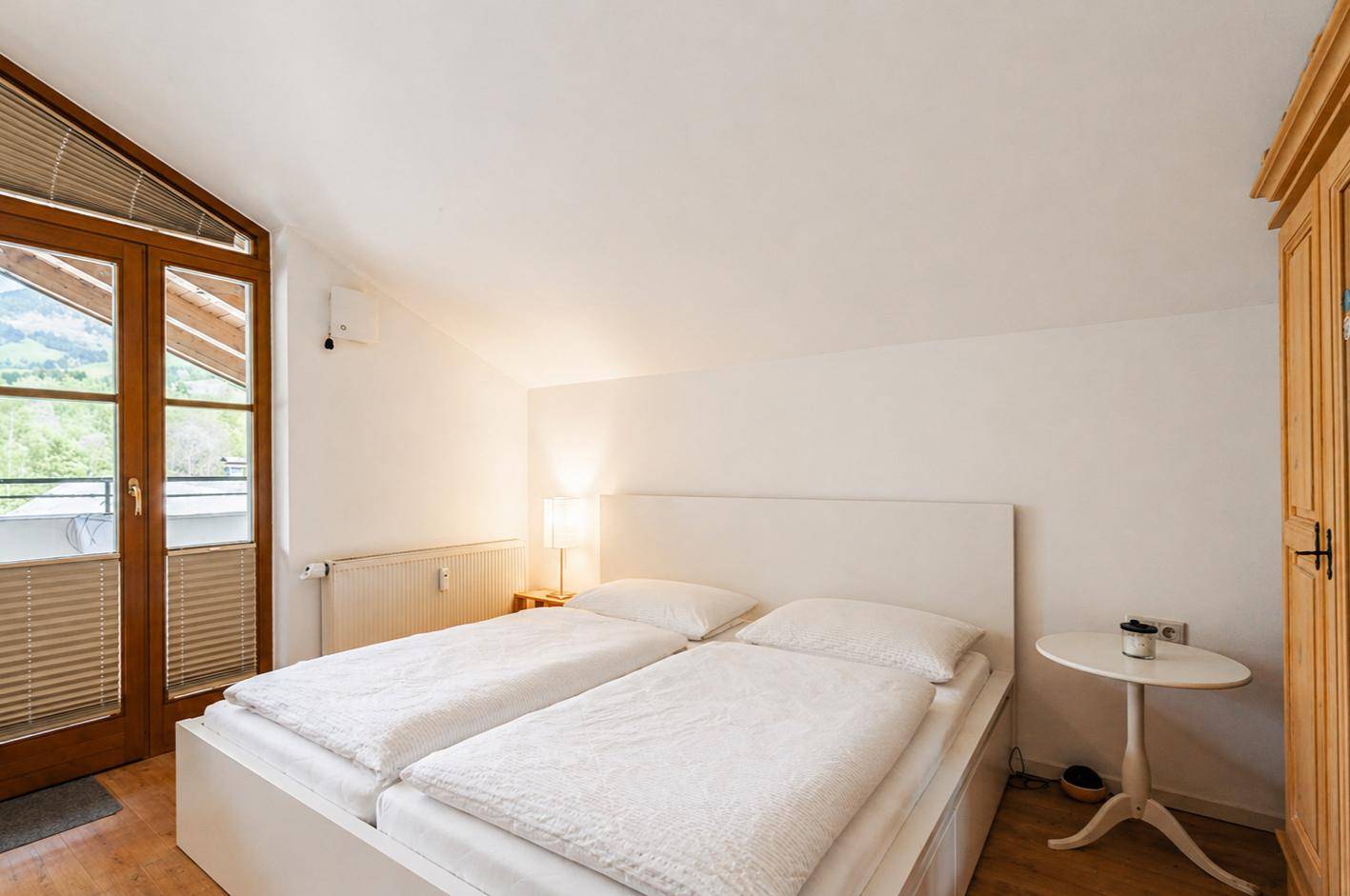 Schlafzimmer mit Zugang zum Balkon und schrägen Decken, bietet eine helle Atmosphäre.