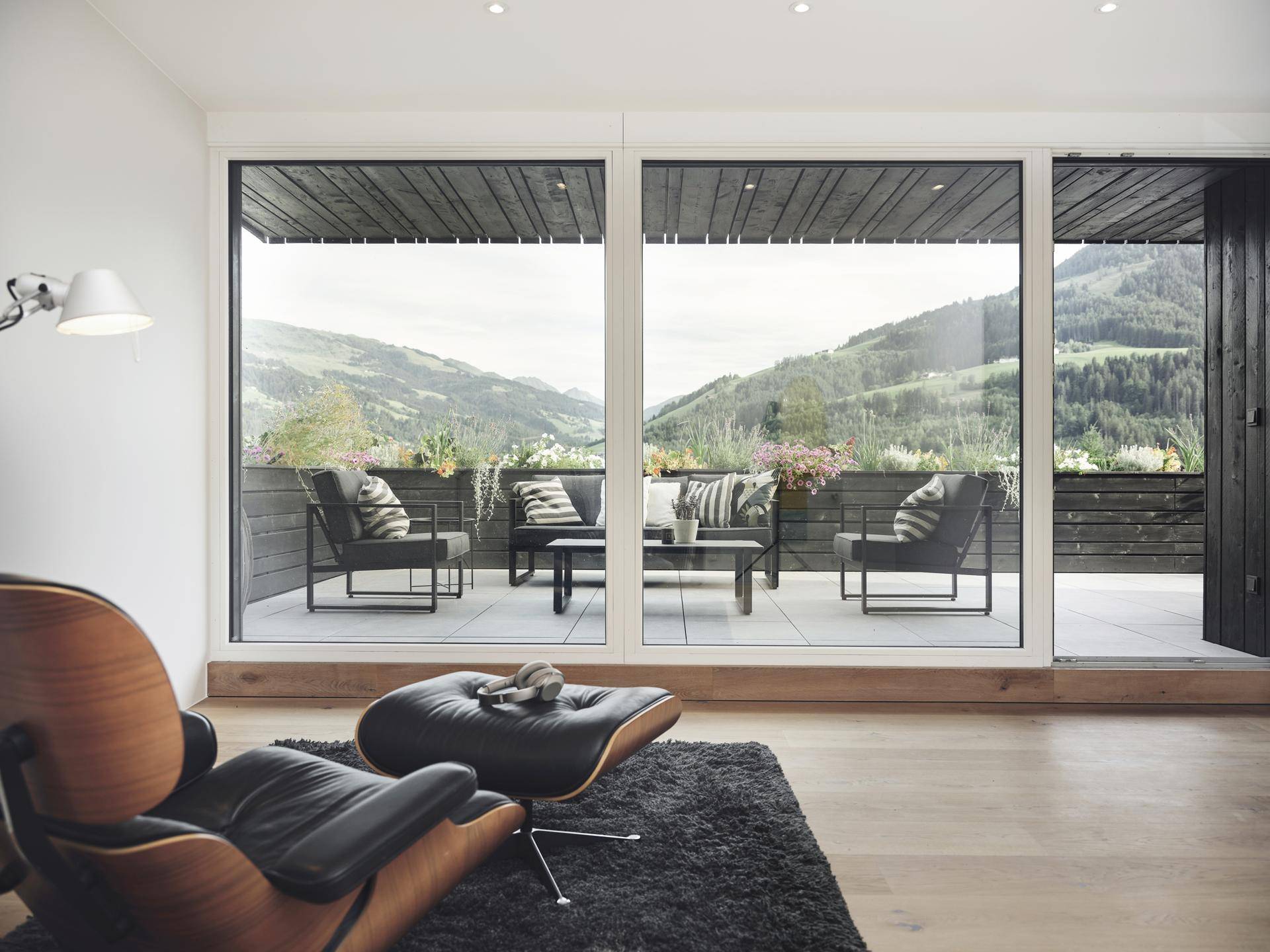 Modernes Wohnzimmer mit bequemen Sesseln und großen Fenstern, die einen Panoramablick auf die Berge bieten.