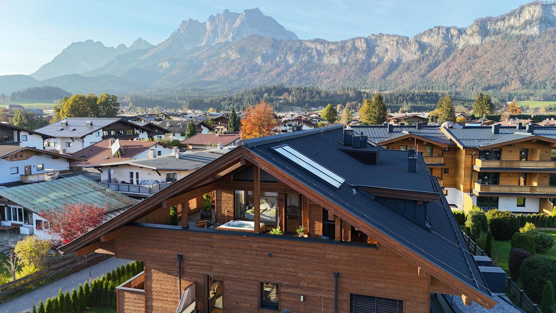 Luftaufnahme eines modernen Chalets mit Holzelementen und Flachdach, eingebettet in eine Berglandschaft.