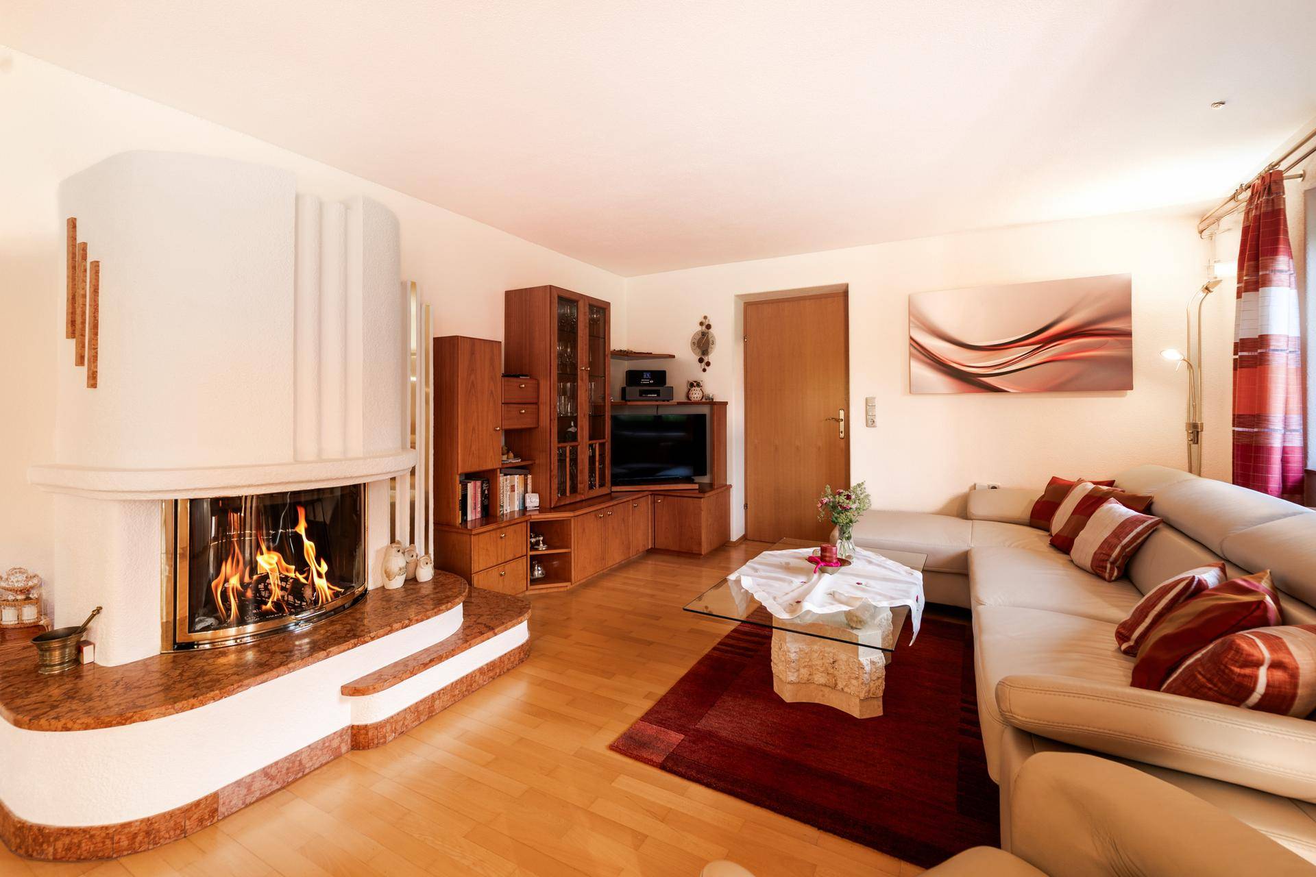 Gemütliches Wohnzimmer mit Kamin, beigem Sofa und warmem Holzfußboden.