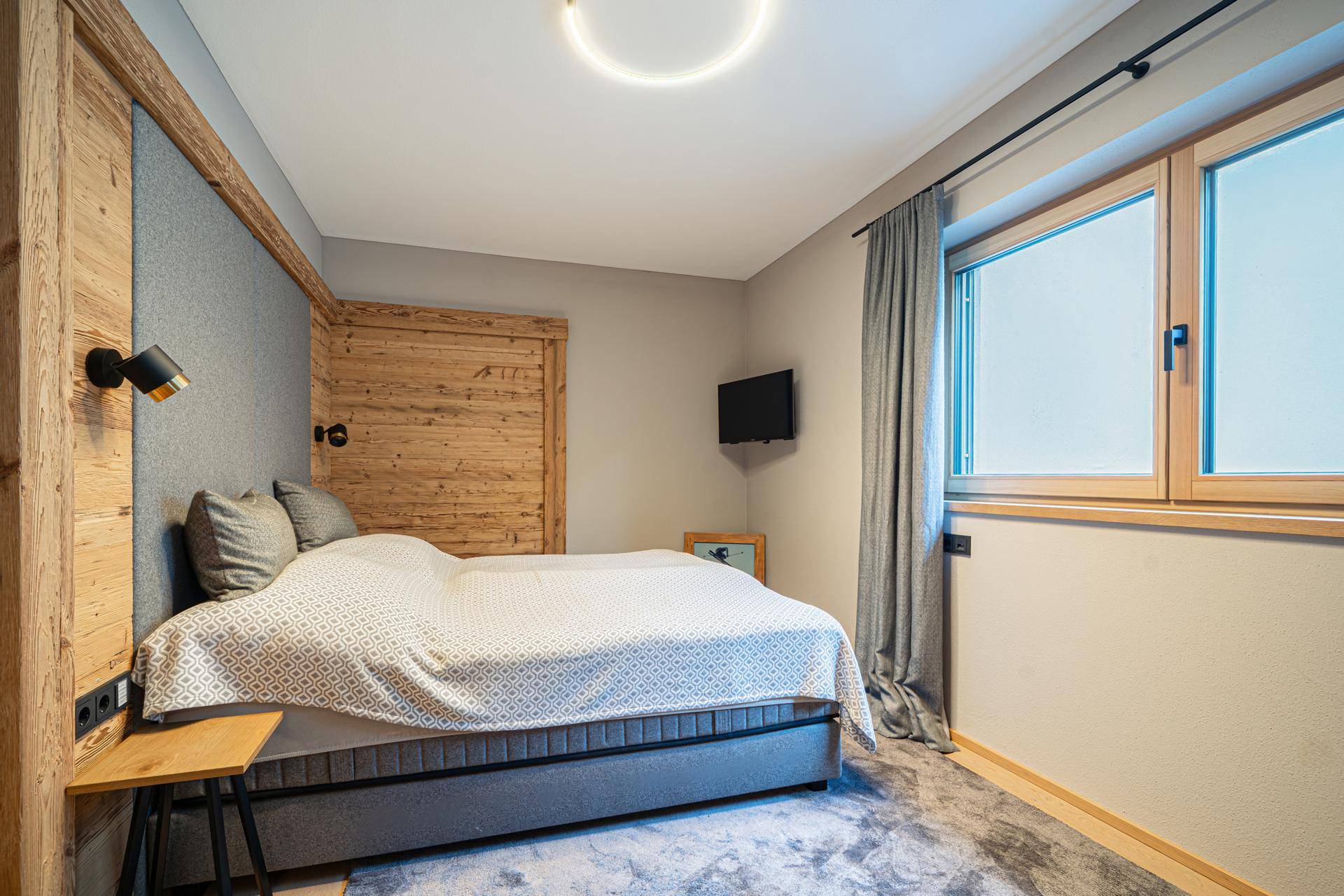 Gemütliches Schlafzimmer mit Holzelementen, Teppichboden und einem Fenster für natürliches Licht.