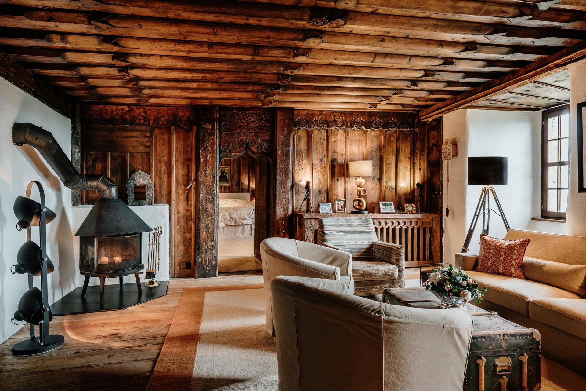 Gemütliches Wohnzimmer mit Holzbalkendecke, Kaminofen und traditioneller Einrichtung.