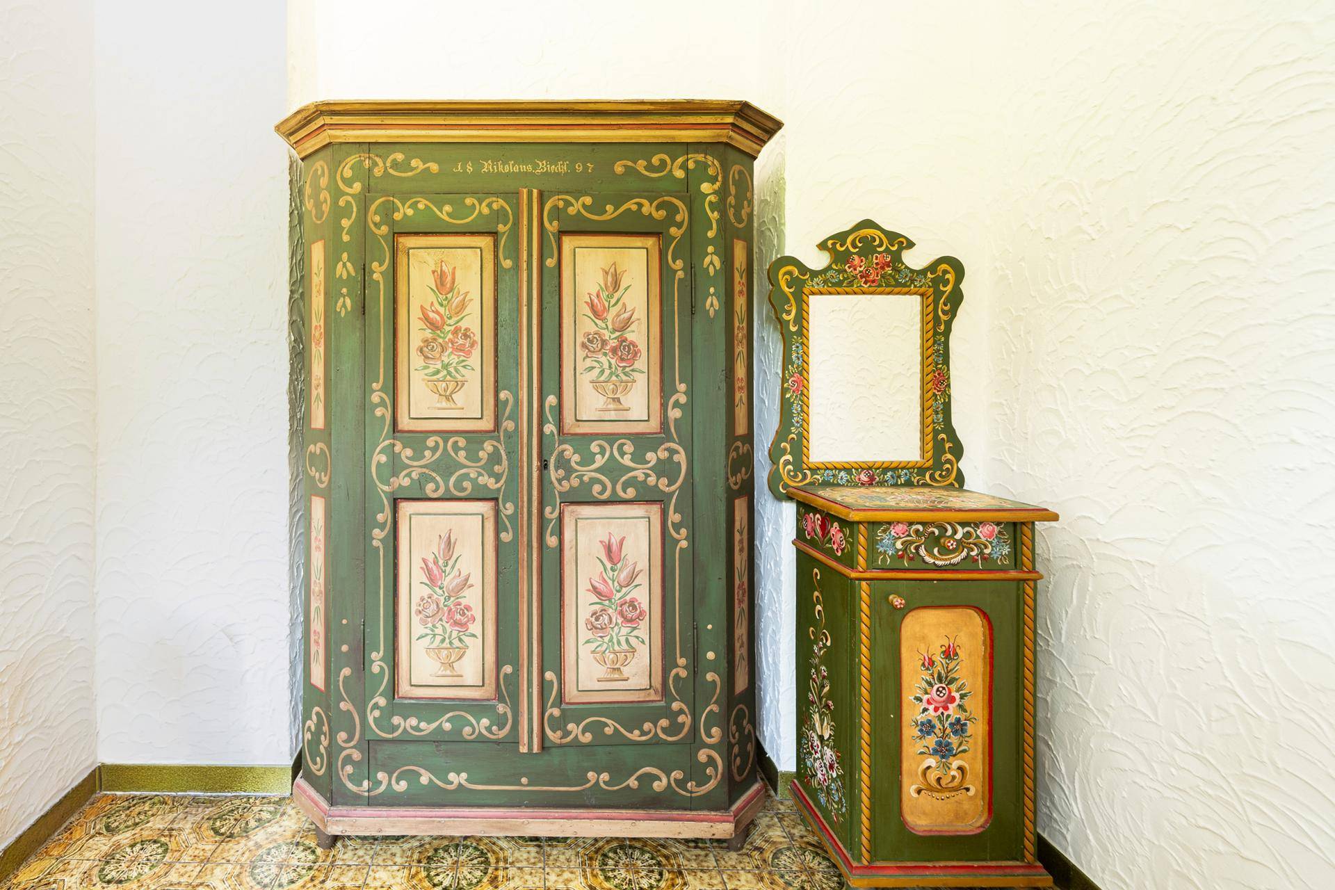 Flur mit kunstvoll bemalten, traditionellen Holzmöbeln und gemustertem Fliesenboden.
