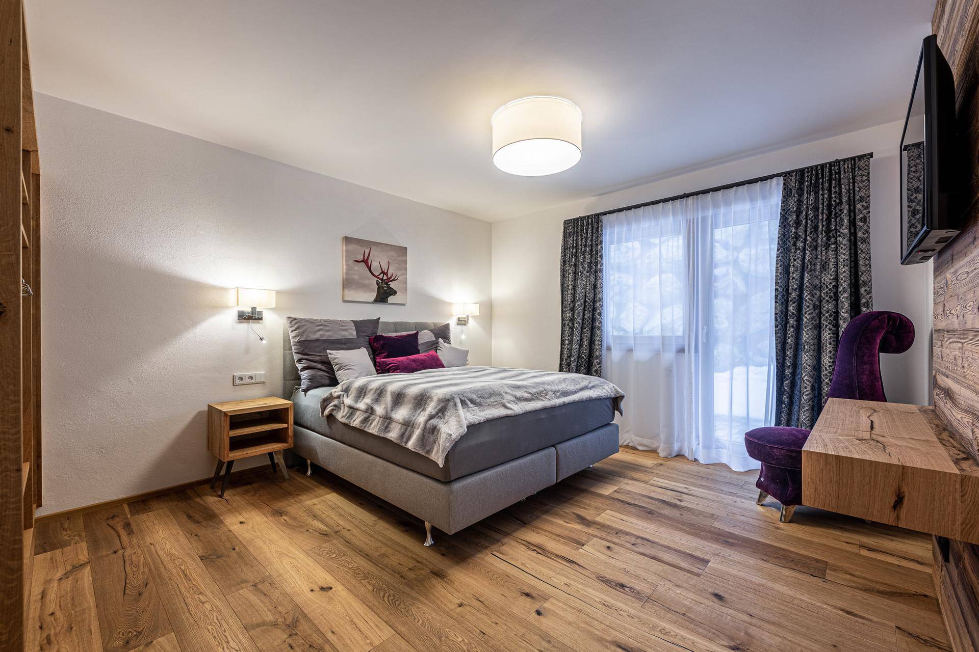 Helles Schlafzimmer mit Holzboden, großem Bett und moderner Wandgestaltung.