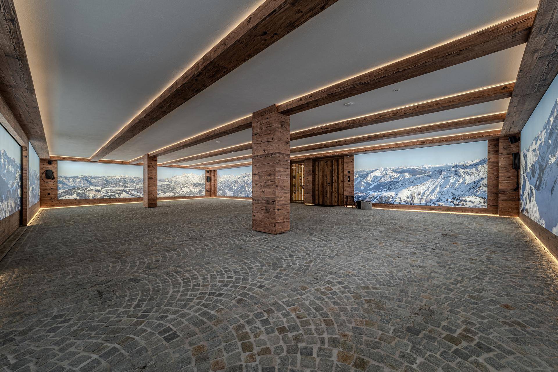 Geräumige Tiefgarage mit Steinpflasterboden und Wandbildern von Berglandschaften.