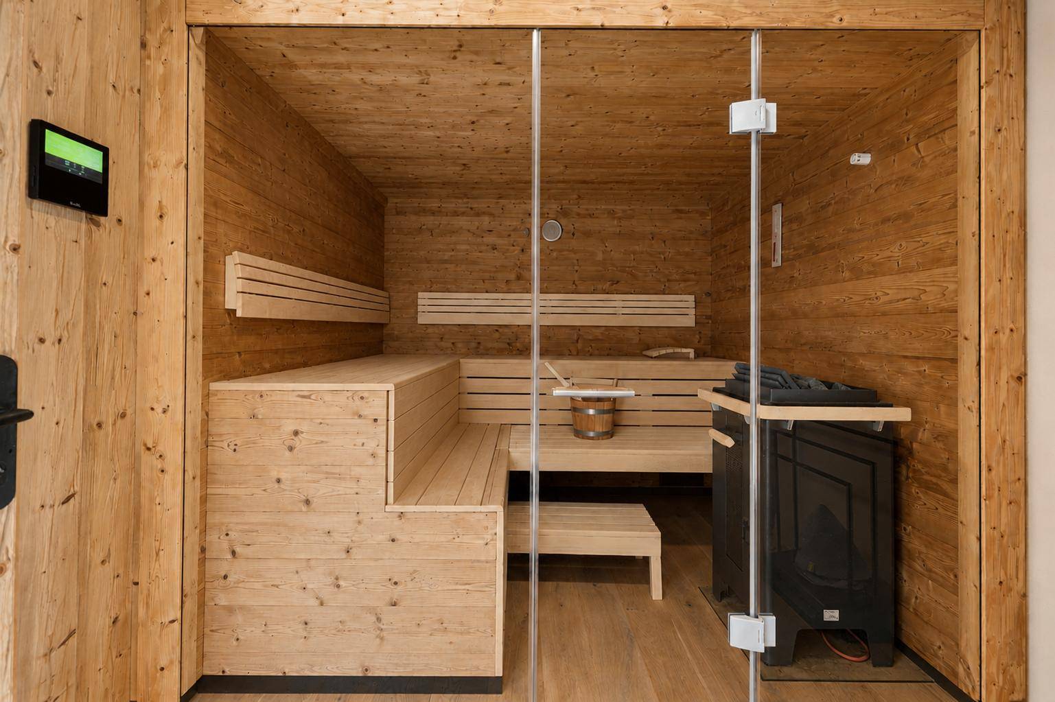 Geräumige Holzsauna mit mehreren Bänken und traditionellem Saunaofen für Entspannung.