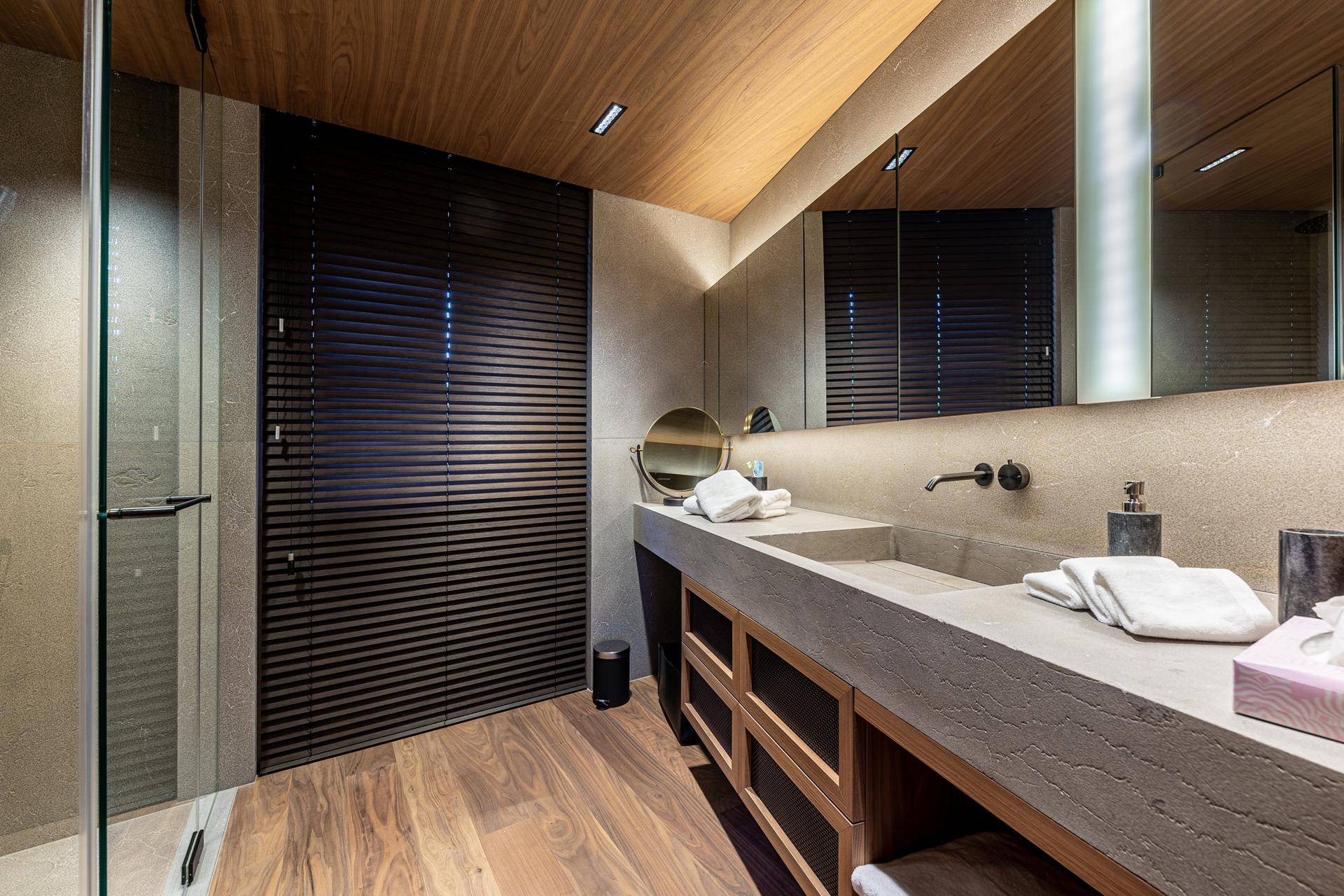 Elegantes Badezimmer mit Doppelwaschbecken, großer Spiegelfläche und Holzboden.