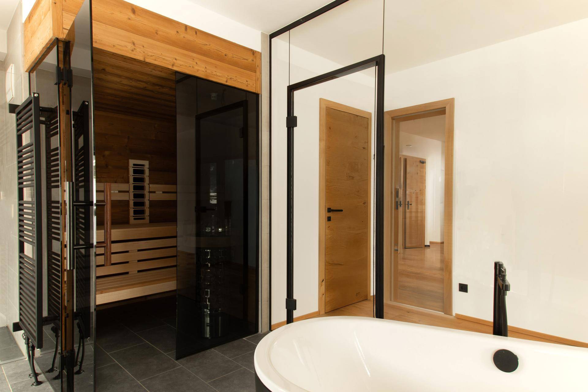 Elegantes Badezimmer mit Badewanne und direktem Zugang zu einer modernen Sauna.