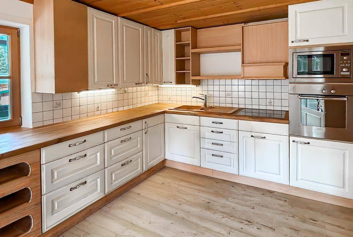 Helle Einbauküche mit weißen Schränken, Holz-Arbeitsplatten und integrierten Elektrogeräten.