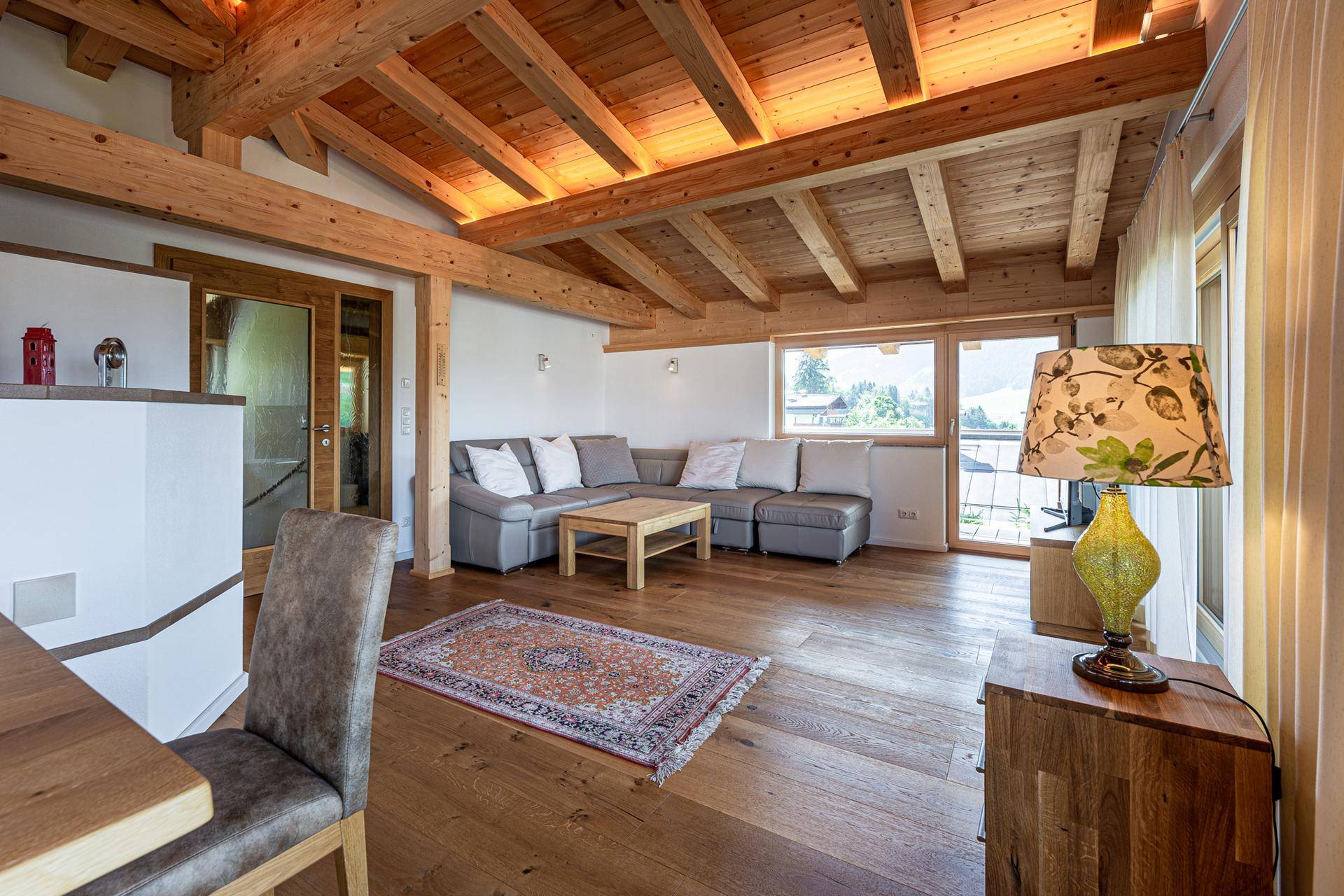 Gemütliches Wohnzimmer mit Holzbalkendecke, Parkettboden und bequemer Sitzecke.
