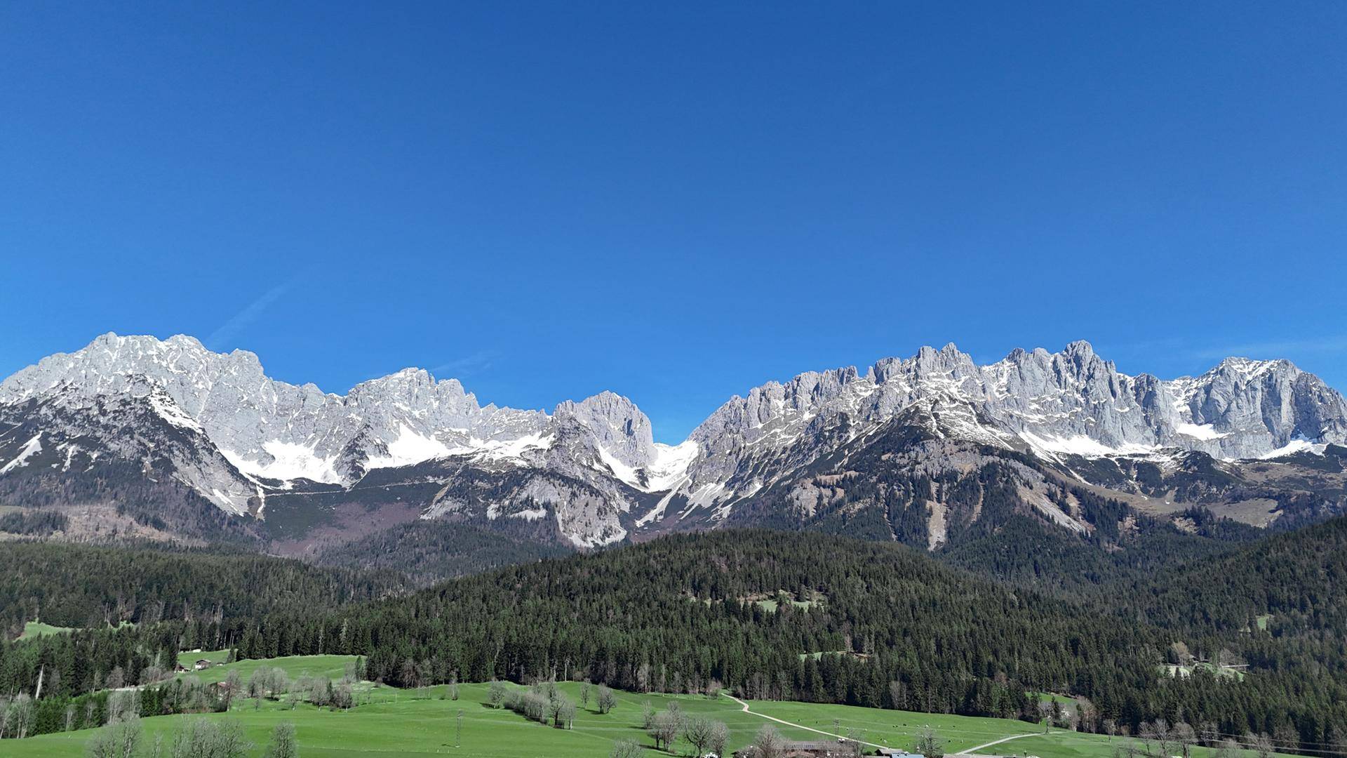 Majestätische Bergkette mit schneebedeckten Gipfeln unter einem strahlend blauen Himmel.