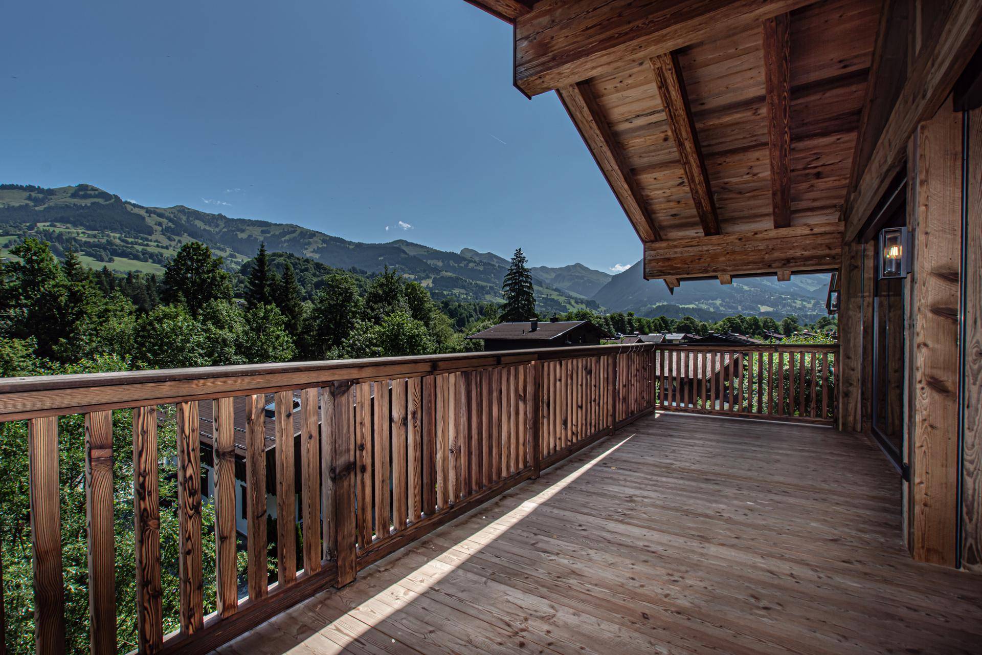 Großer Holzbalkon mit Panoramablick auf die umliegende Berglandschaft und grüne Wälder.