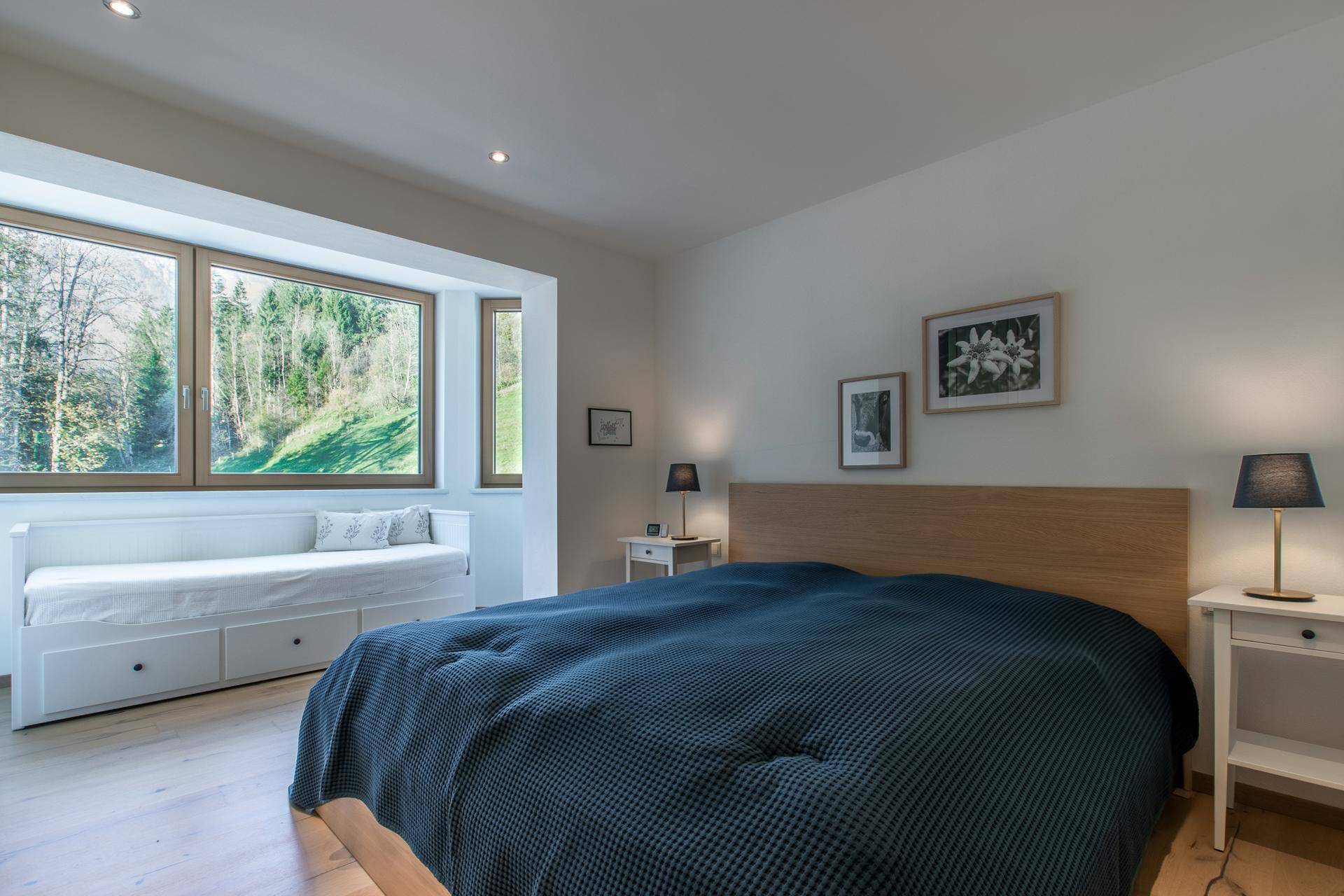 Helles Schlafzimmer mit Doppelbett, Tagesbett am Fenster und Blick ins Grüne.
