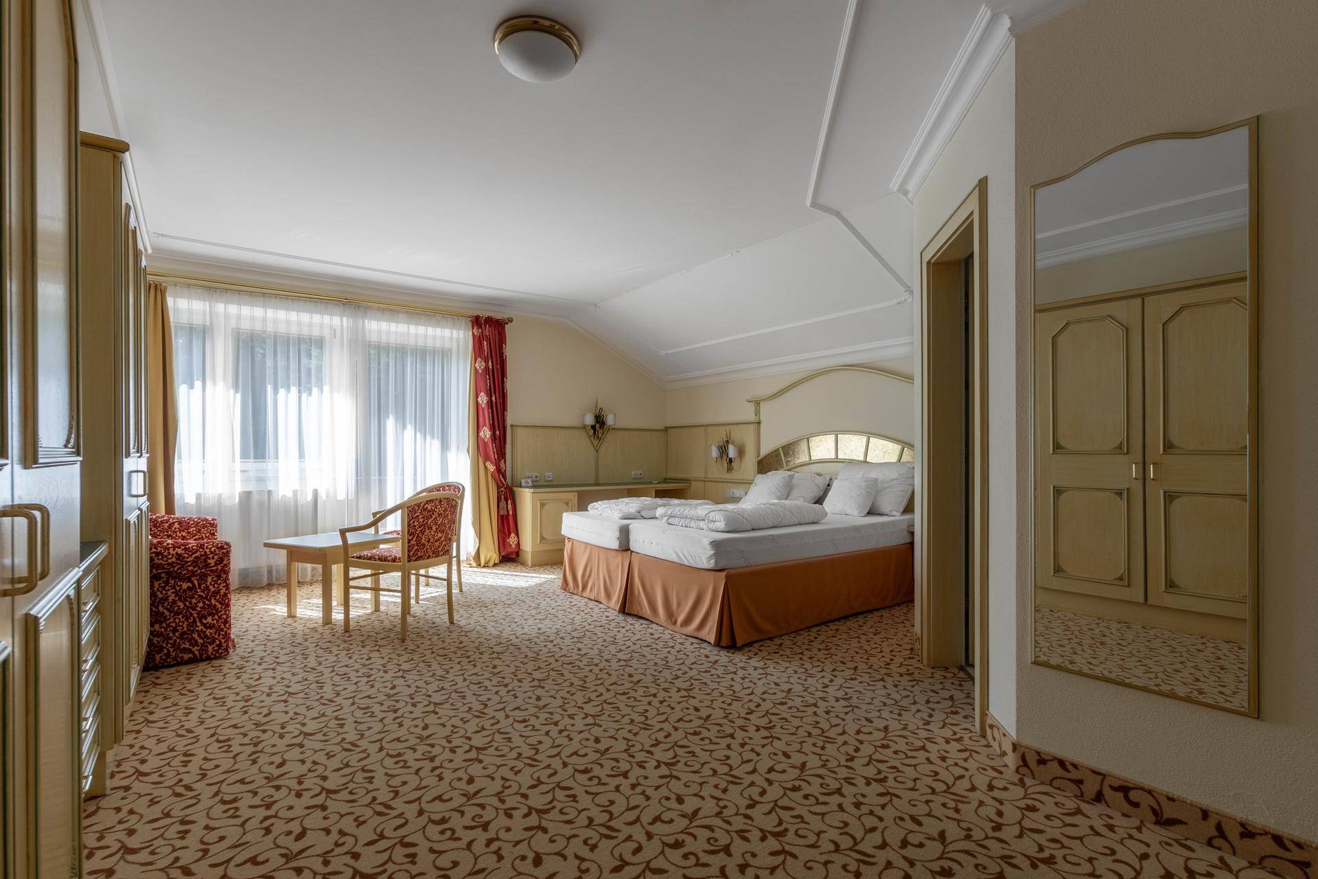 Gemütliches Schlafzimmer mit Doppelbett, Teppichboden, Schränken und einem Fenster mit Vorhängen.