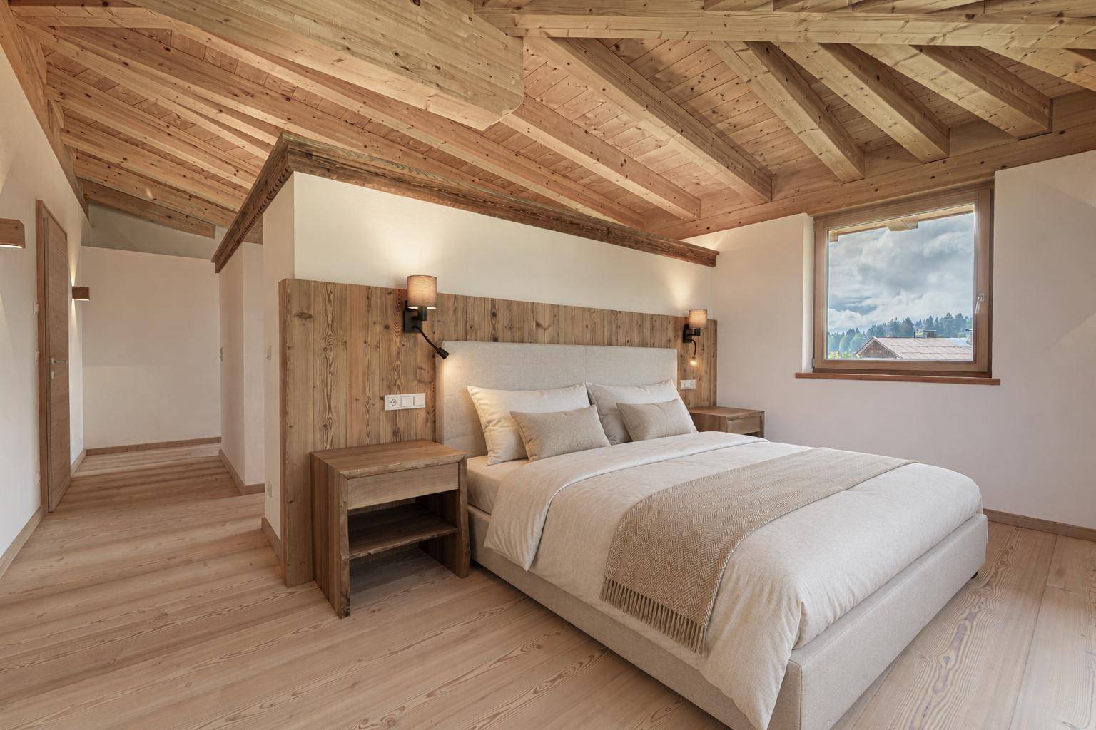 Gemütliches Schlafzimmer mit Holzbalkendecke, modernem Bett und einem Fenster mit Blick in die Natur.