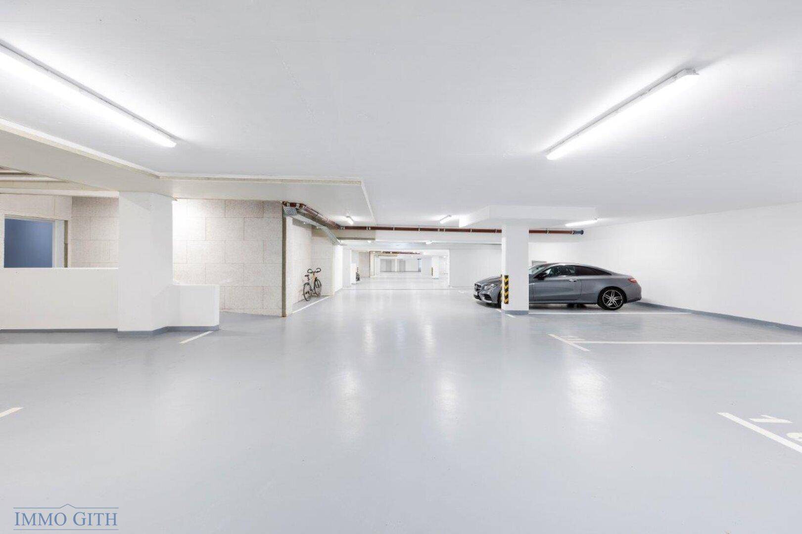 Saubere Tiefgarage mit einem geparkten Auto und einem Fahrrad, bietet ausreichend Platz und gute Beleuchtung.
