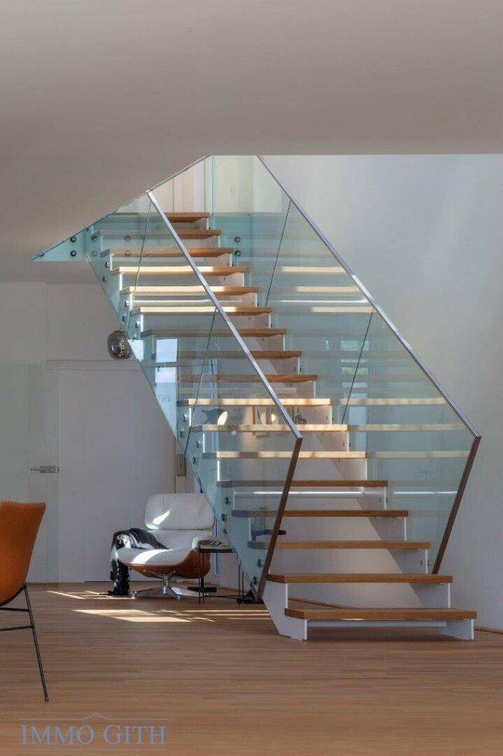 Elegante Holztreppe mit Glasgeländer, die viel natürliches Licht in den Raum lässt.