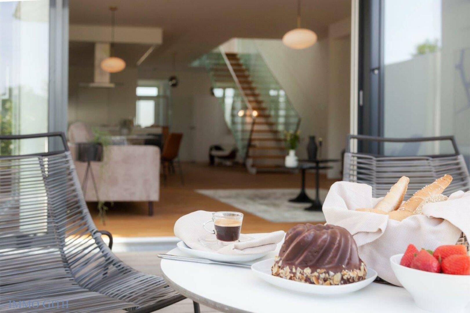 Frühstück auf der Terrasse mit Kuchen, Kaffee und frischen Erdbeeren, Blick ins Haus.