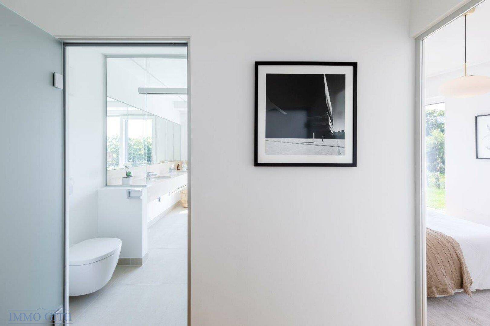Heller Flur mit Zugang zu einem modernen Badezimmer und einem Schlafzimmer.