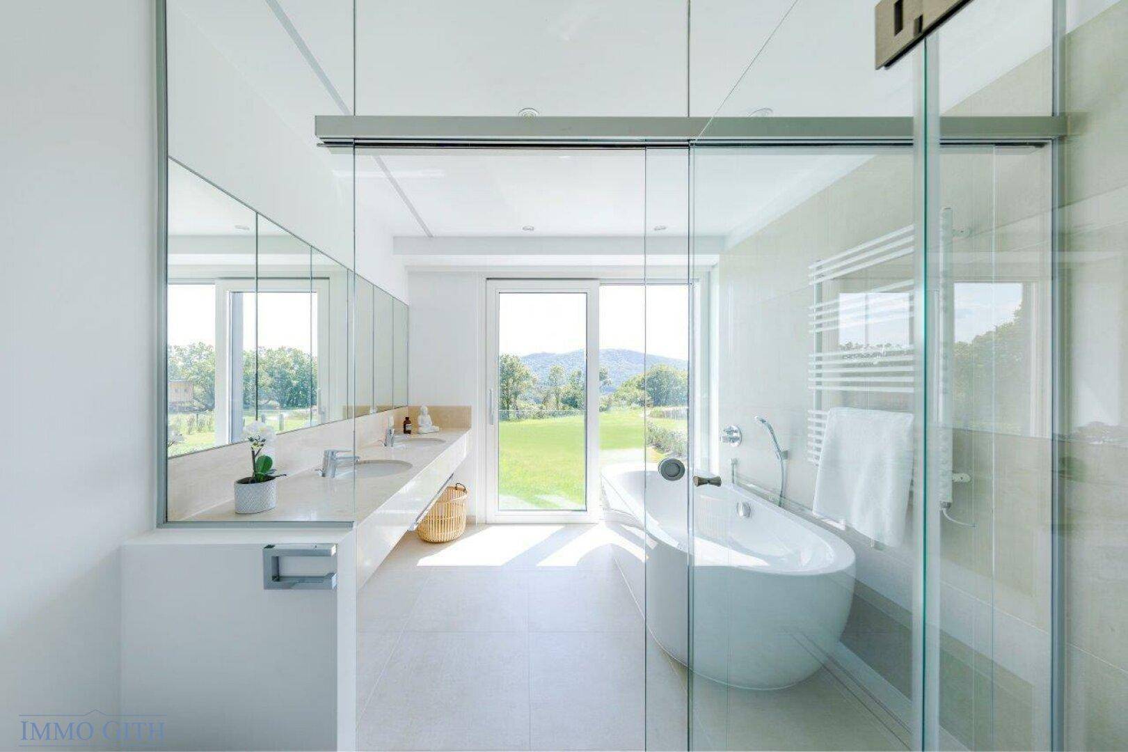 Luxuriöses Badezimmer mit freistehender Badewanne, Doppelwaschbecken und Panoramablick.