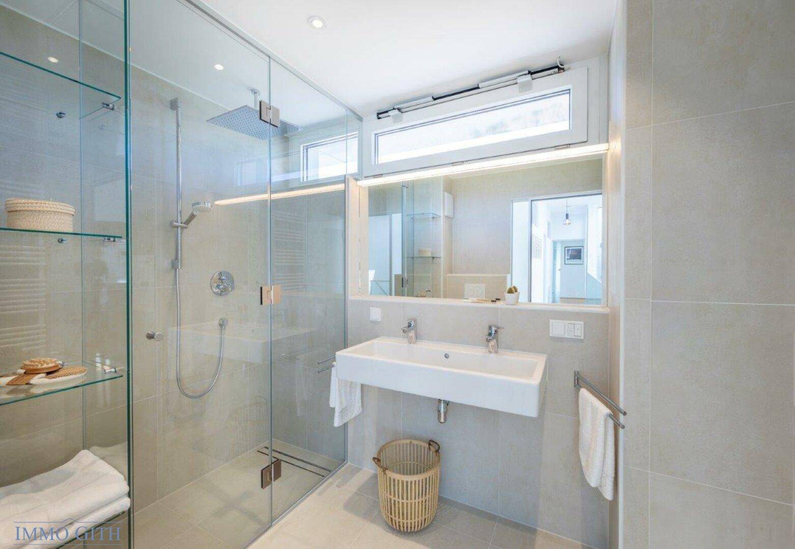Modernes Badezimmer mit begehbarer Dusche, Doppelwaschbecken und großformatigen Fliesen.