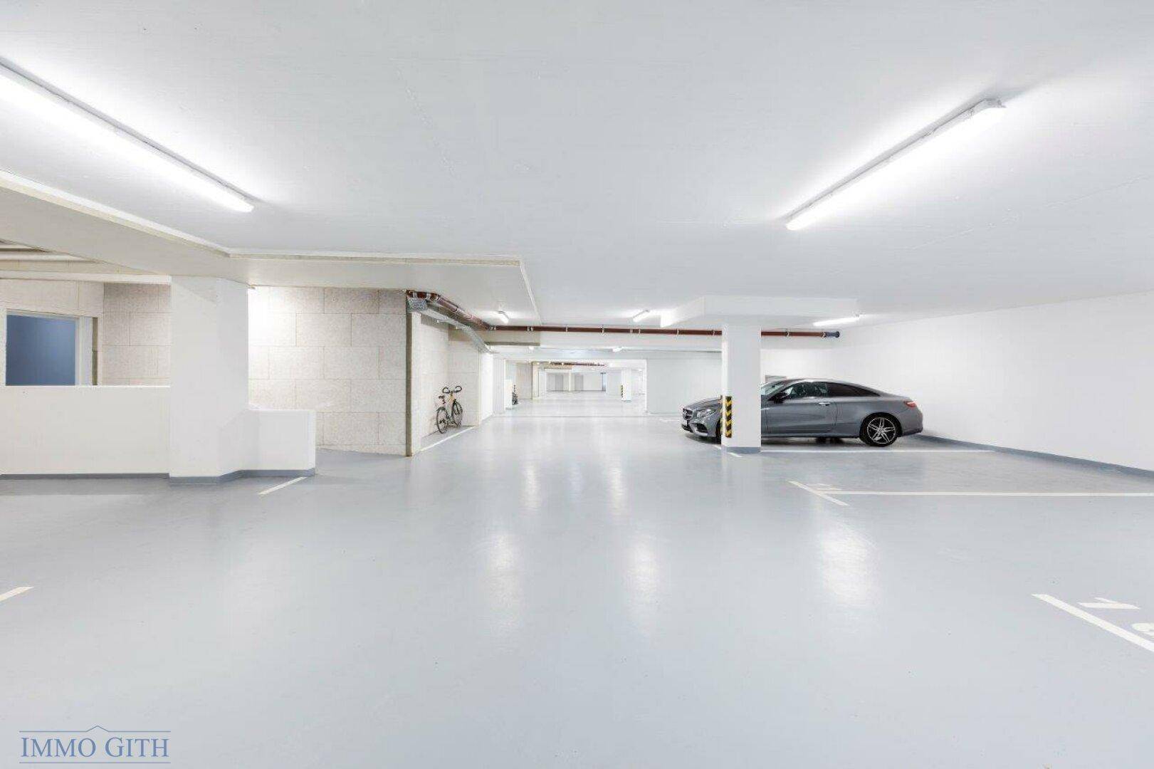 Helle und saubere Tiefgarage mit ausreichend Stellplätzen und einem geparkten Auto.