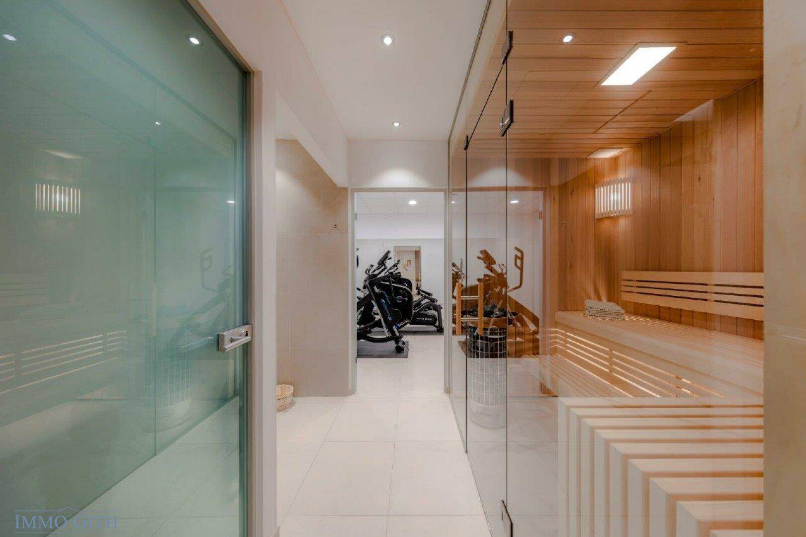 Wellnessbereich mit Sauna und Blick auf den angrenzenden Fitnessraum.