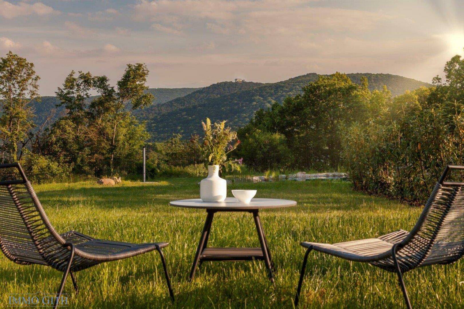 Gemütlicher Sitzbereich im Garten mit Blick auf die umliegende Natur und Berge.