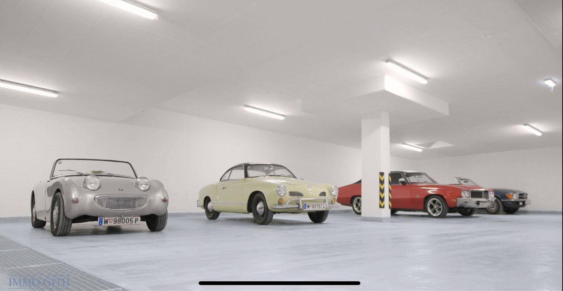 Geräumige Tiefgarage mit mehreren Oldtimern und heller Beleuchtung.