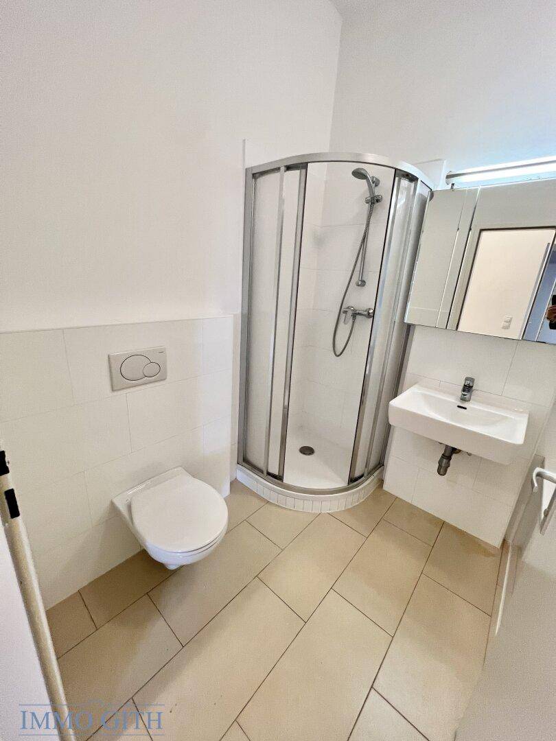 Modernes Badezimmer mit Duschkabine, wandhängendem WC und hellem Fliesenboden, funktional und sauber.