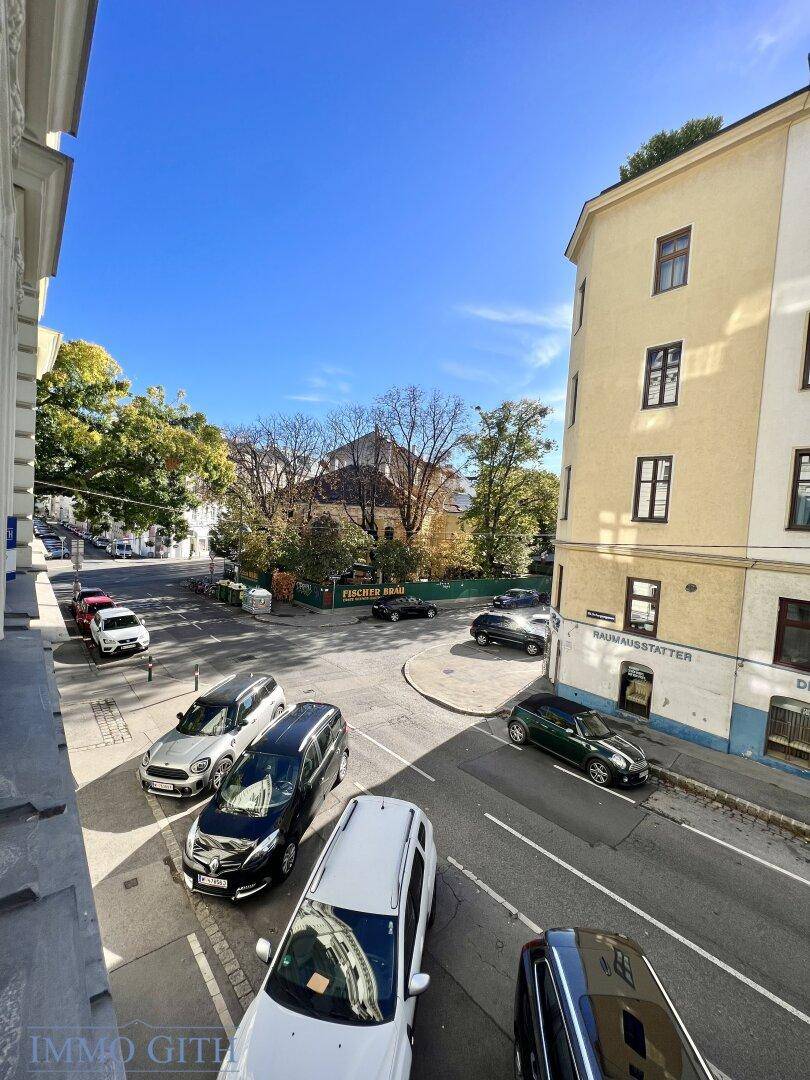 Blick von oben auf eine belebte Straßenkreuzung mit parkenden Autos und umliegenden Gebäuden.