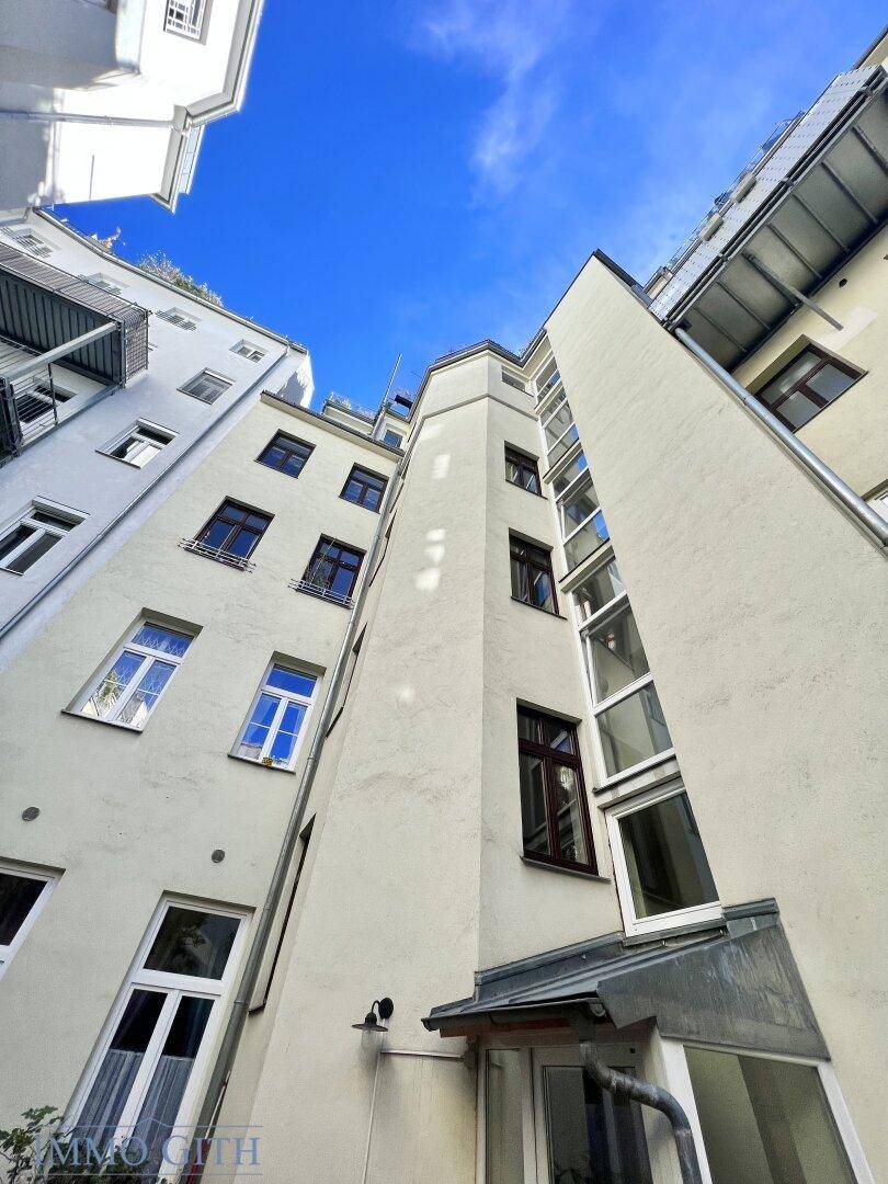 Blick nach oben auf die hohen Fassaden der umliegenden Gebäude im Innenhof, beeindruckende Architektur.
