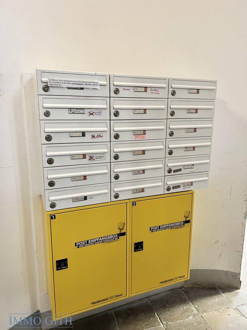 Wand mit Briefkästen und Paketempfangsboxen im Eingangsbereich des Gebäudes, praktisch für Bewohner.