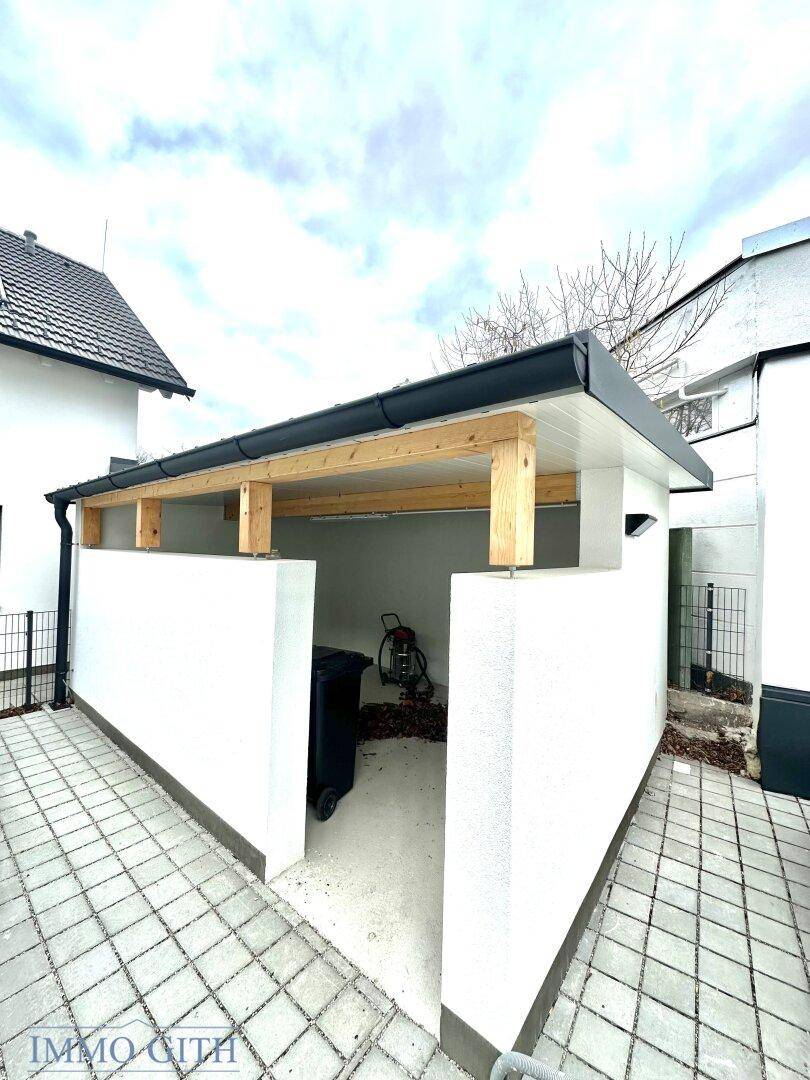 Überdachter Bereich mit Holzbalken, der als Carport oder Abstellraum genutzt werden kann.