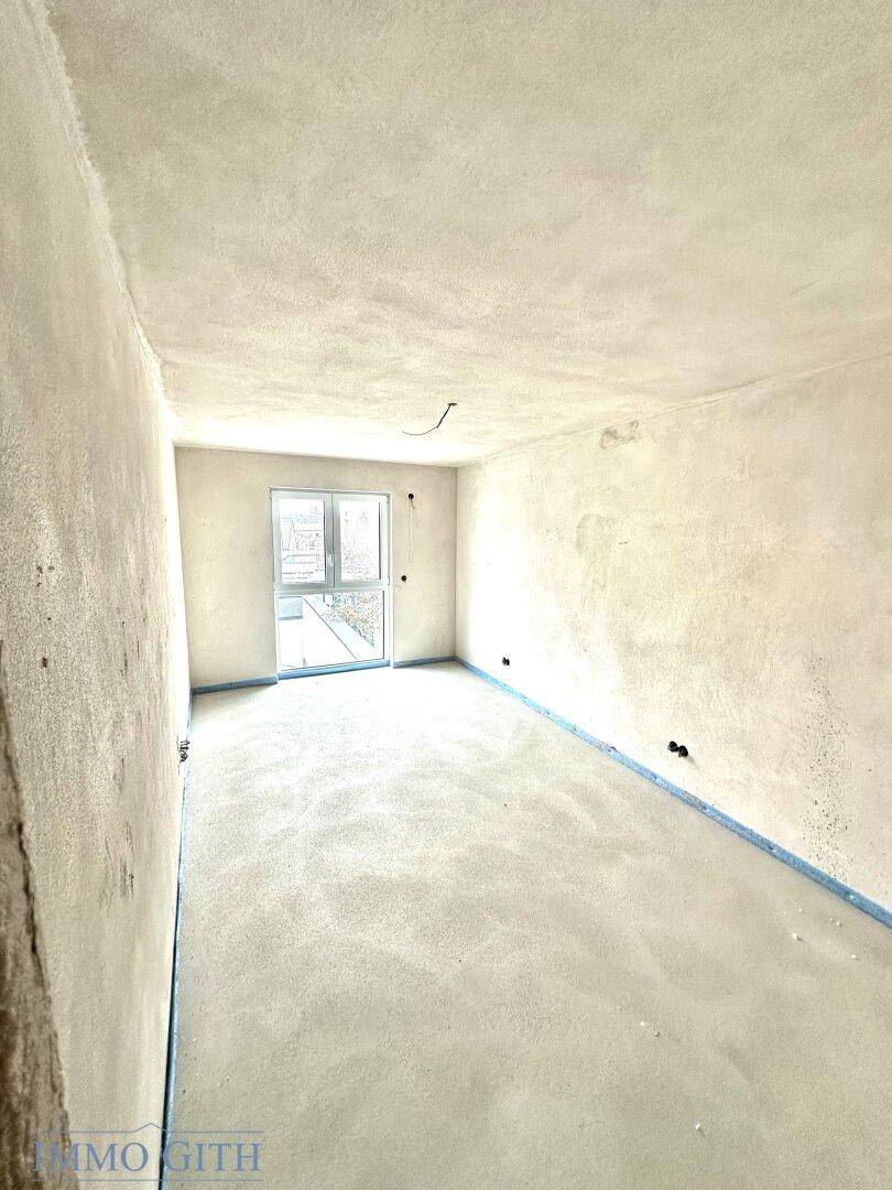 Unfertiger Raum mit einem Fenster und vorbereiteten Wänden, bereit für die individuelle Gestaltung und Einrichtung.