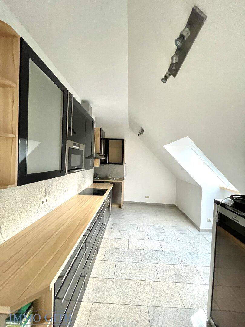 Moderne Küche mit Holz-Arbeitsplatte, schwarzen Schränken und einem Dachfenster für natürliches Licht.