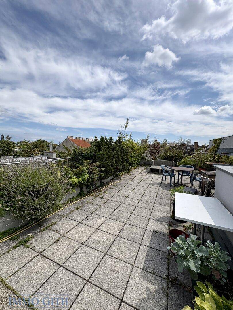 Geräumige Dachterrasse mit Fliesenboden und Blick über die Dächer der Stadt.