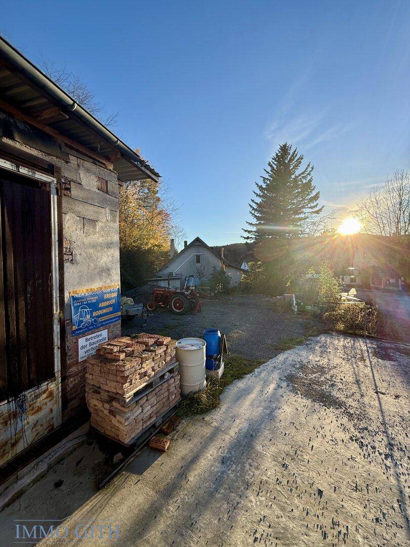 Ein älterer Schuppen mit Ziegeln und einem Hofbereich im warmen Licht der Herbstsonne.
