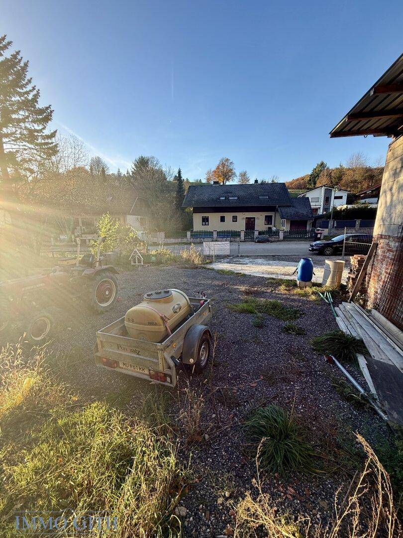 Ländliches Anwesen mit einem Schuppen, einem Anhänger und einem Haus im Hintergrund.