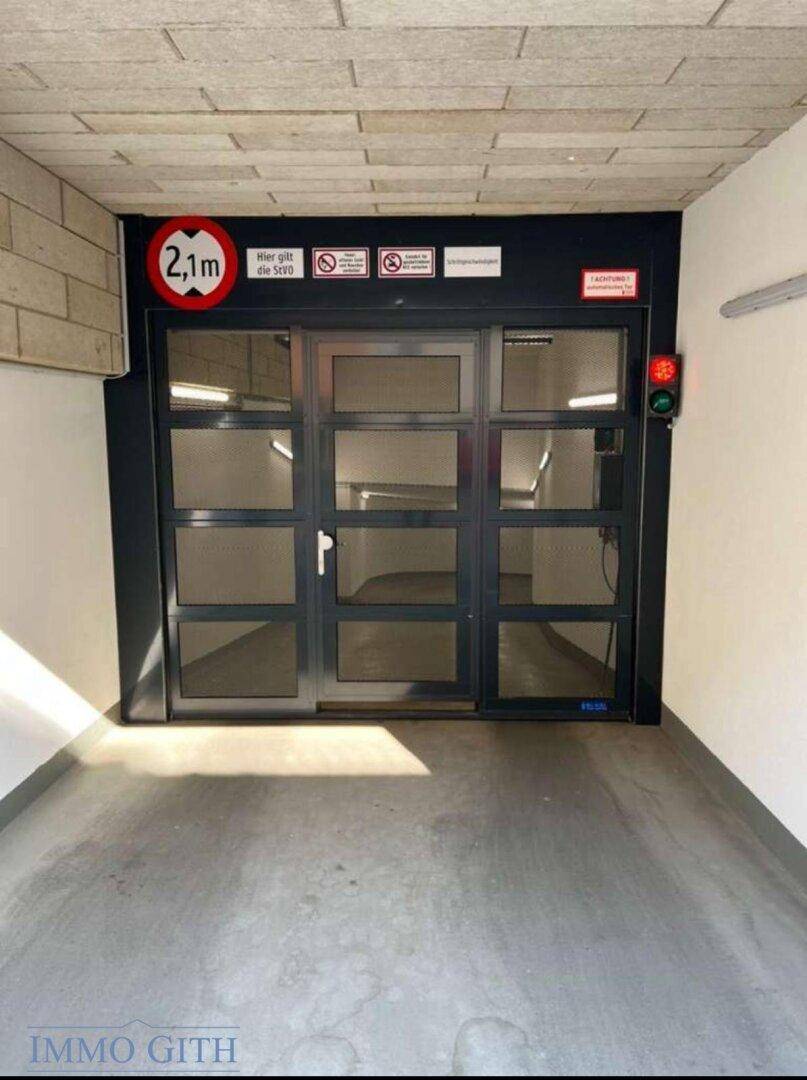 Eingangsbereich der Tiefgarage mit Höhenbegrenzung von 2,1 Metern und Sicherheitshinweisen.