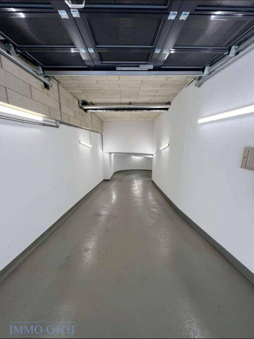 Geschwungene Rampe in der Tiefgarage mit heller Beleuchtung und glattem Boden für Fahrzeuge.