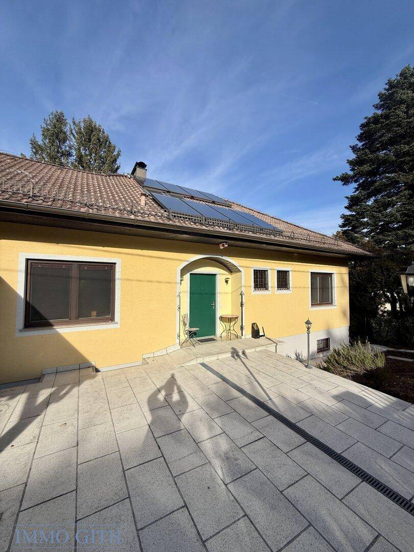 Eingangsbereich des Hauses mit gepflastertem Vorplatz und Photovoltaikanlage.