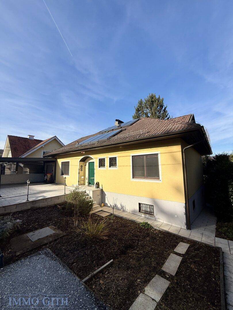 Gelbes Einfamilienhaus mit Photovoltaikanlage und kleinem Vorgarten.
