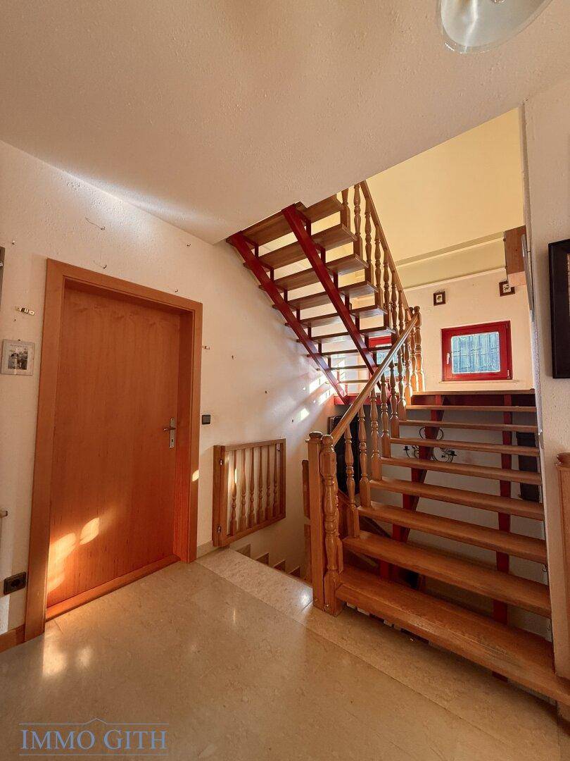 Heller Flur mit Holztreppe, die in die oberen Stockwerke führt.
