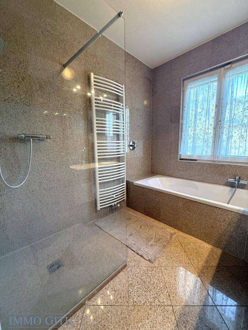 Modernes Badezimmer mit begehbarer Dusche, Badewanne und beheiztem Handtuchhalter.