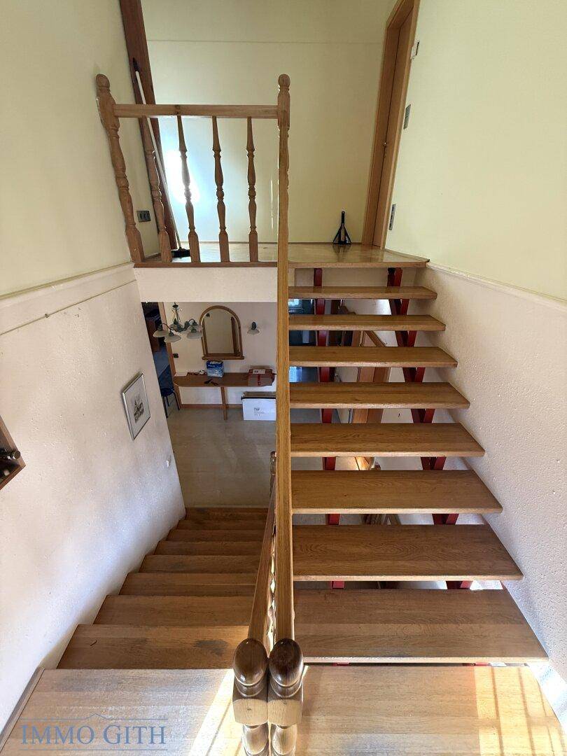Blick von oben auf die Holztreppe, die den Flur mit den oberen Etagen verbindet.