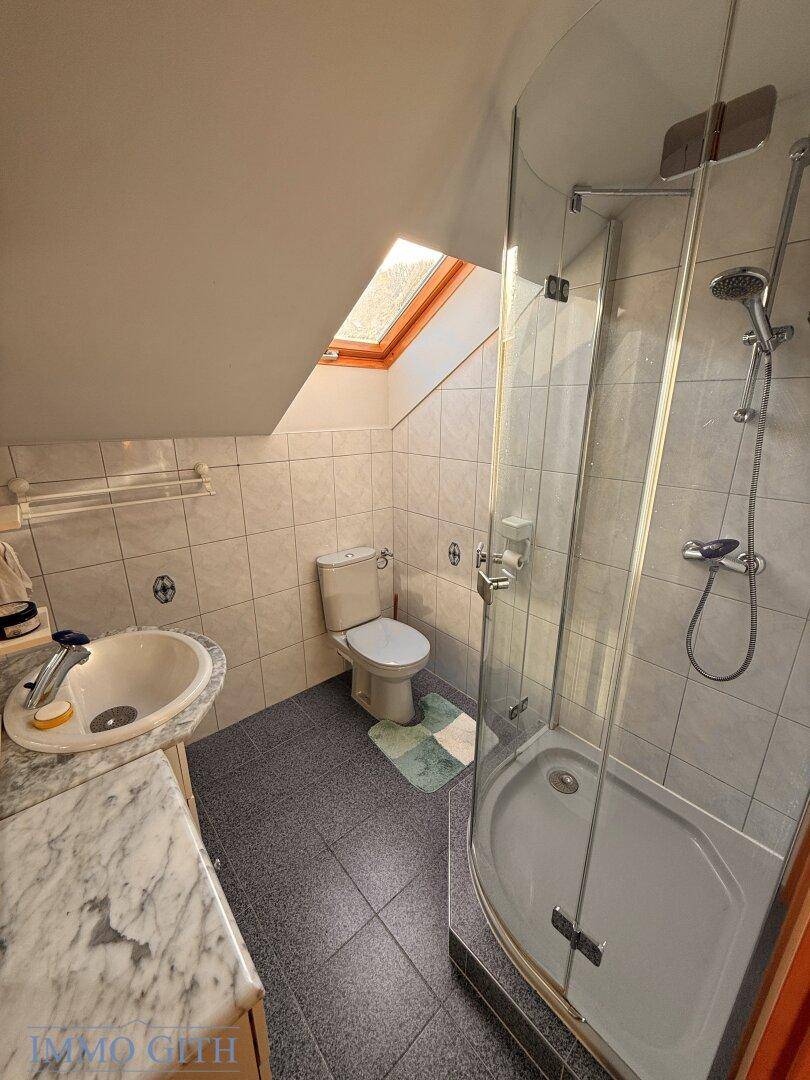 Badezimmer im Dachgeschoss mit Dusche, WC, Waschbecken und Dachfenster.