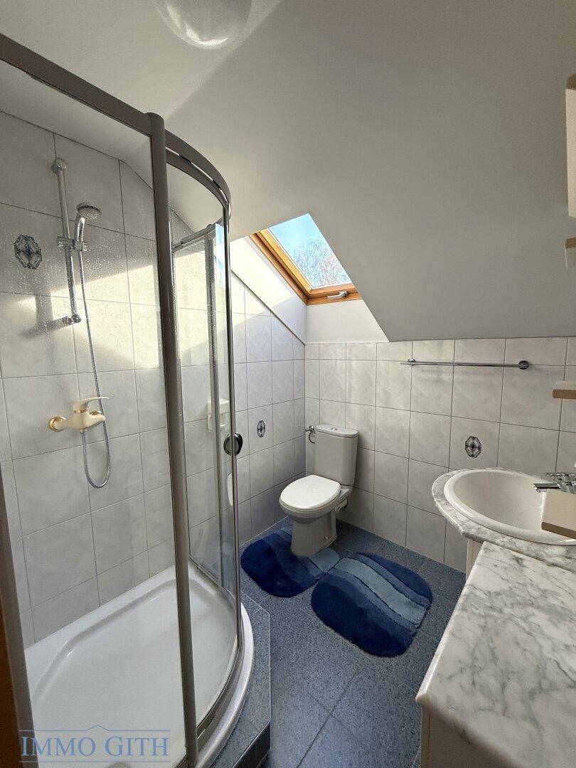 Helles Badezimmer im Dachgeschoss mit Dusche, WC und Dachfenster.
