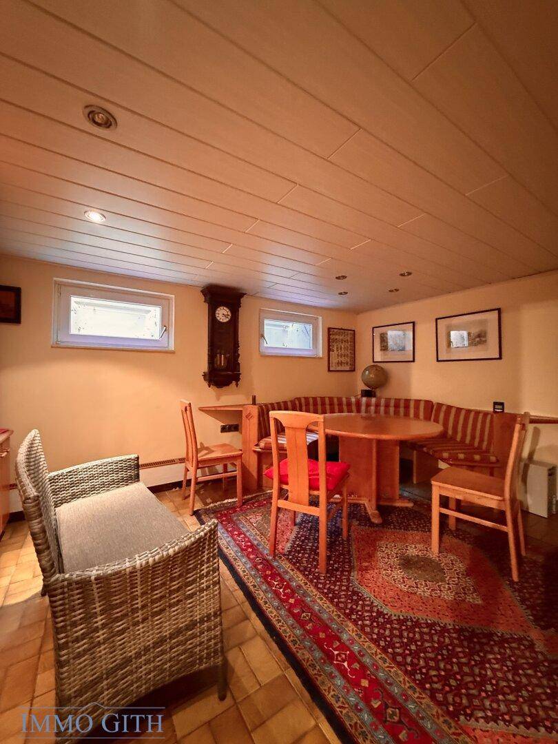 Gemütlicher Essbereich mit Holztisch, Sitzbank und traditionellem Teppich.